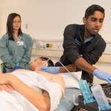 A medical student performs an ultrasound under faculty supervision.