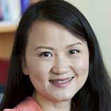 Dr. Jasmine Zhou, smiling, wearing a coral blouse.