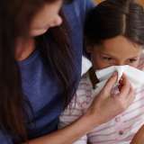 Mom blows her daughter's stuffy nose.