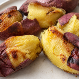 Roasted purple-skinned sweet potato halves on white plate