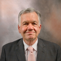 headshot of doctor greg Brent in grey suit
