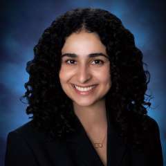 Head shot of Nicki Karimi-Mostowfi in a black suit jacket, smiling at the camera