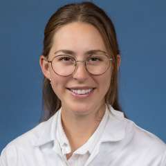 Head shot of Clare Schrodt in white lab coat, smiling at camera