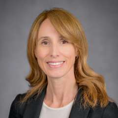 Smiling professional headshot of woman with light brown hair in black blazer