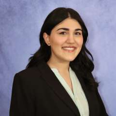 Three-quarters shot of Vista Farkhondeh, MD, in business attire, smiling at camera