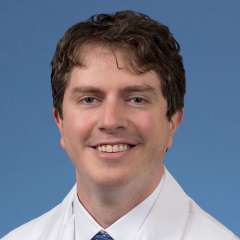 Head shot of Dylan Calame in a white coat, looking at camera