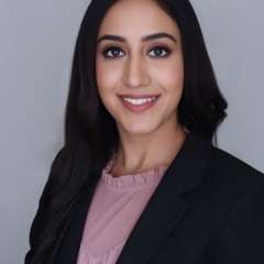Headshot of Simrat in a black suit with pink shirt 