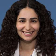 Head shot of Nicki Karimi-Mostowfi, MD in white coat, smiling at the camera