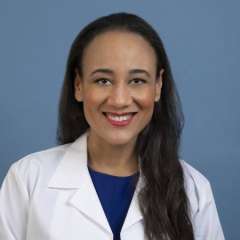 Headshot of Ashley Prosper wearing a white lab coat on a blue background.