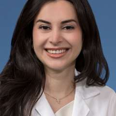 Head shot of Natalie Nabaty, MD in white coat, smiling at the camera
