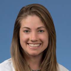 Head shot of Neva Lundy in a white coat, smiling at camera