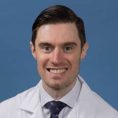 Head shot of John Thompson in white lab coat, smiling at camera