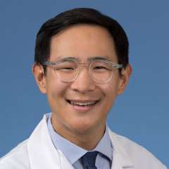 Head shot of Jerry Shen in a white coat, smiling at camera