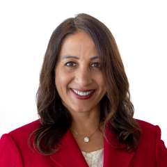 Dr. Nimmi Kappor smiling in red blazer headshot on white background