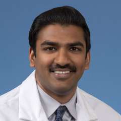 Head shot of Rohan Rao in a white coat, smiling at camera