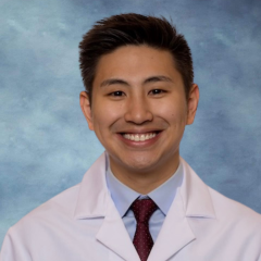 Dr. Jason Tang wearing a lab coat in front of a blue background