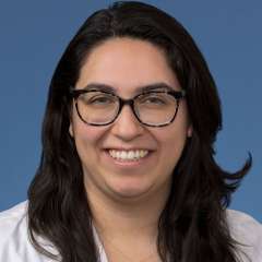 Head shot of Brenda Gutierrez, MD, PhD in a white coat, smiling at the camera