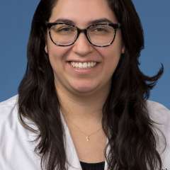 Head shot of Brenda Gutierrez, MD, PhD in a white coat, smiling at the camera
