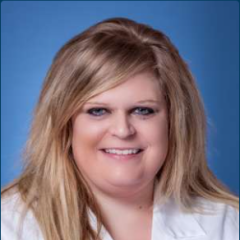 Smiling woman wearing white lab coat portrait against blue background.
