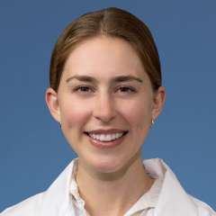 Head shot of Clare Schrodt, MD in white lab coat, smiling at camera