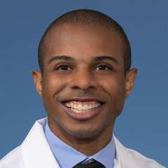 Head shot of Paul Lewis, MD, MS in white coat, smiling at camera