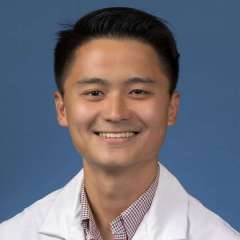 Dr. Matthew Du smiling at camera in a white coat