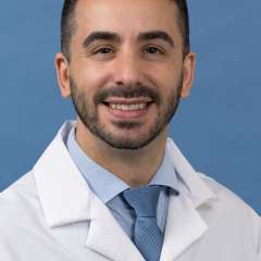 White coat head shot of Borja Sanz Cuesta, smiling at the camera