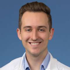 Head shot of Brendan Colgan MD, in white coat, smiling at camera