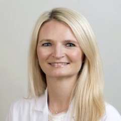 Dr. Susan McCloskey in a white lab coat with blonde hair.
