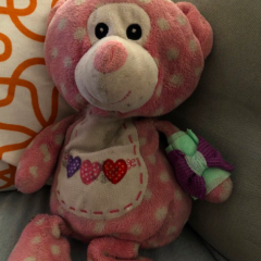 a pink polkadot teddy bear resting on a couch