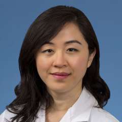 Head shot of Irma Zhang in a white coat, smiling at camera.