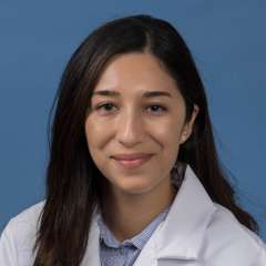 Head shot of Adrianna Carrasco in white lab coat, smiling at camera