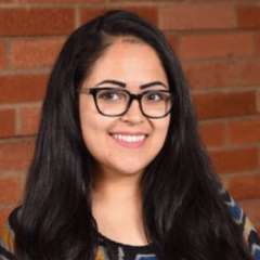 Headshot of Norma Sandoval with red brick wall in the background