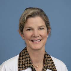 Joann G. Elmore, MD, MPH smiling in a white coat against a blue background
