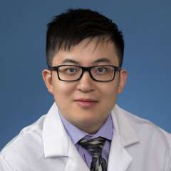 Head shot of Yuxing Xia in white lab coat, looking at camera