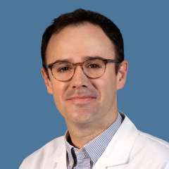 Headshot of Samuel Good, MD, wearing a white coat against a blue background.