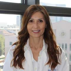 Portrait of Aksone Nouvong, DPM, in a white coat with a blurred face.