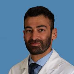 Person in white coat and tie against blue background