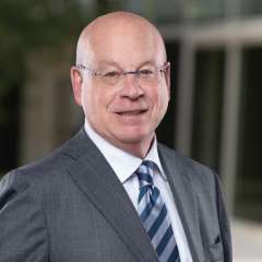 Dr. Michael Steinberg, wearing glasses and a dark suit with striped tie, smiling in a professional headshot.