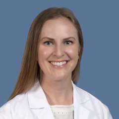 Headshot of Arissa Young, MD, in a white lab coat against a blue background.